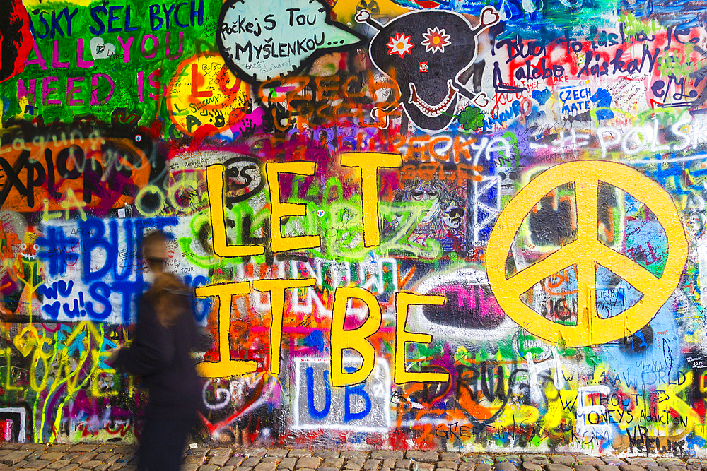 A woman passing by the colourful John Lennon Wall, Lesser Town, Prague (Czechia), Europe