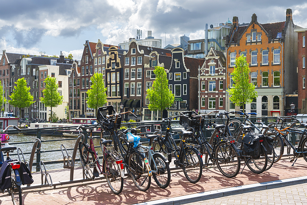 Bicycles with houses by Amstel River in the background, Amsterdam, The Netherlands, Europe