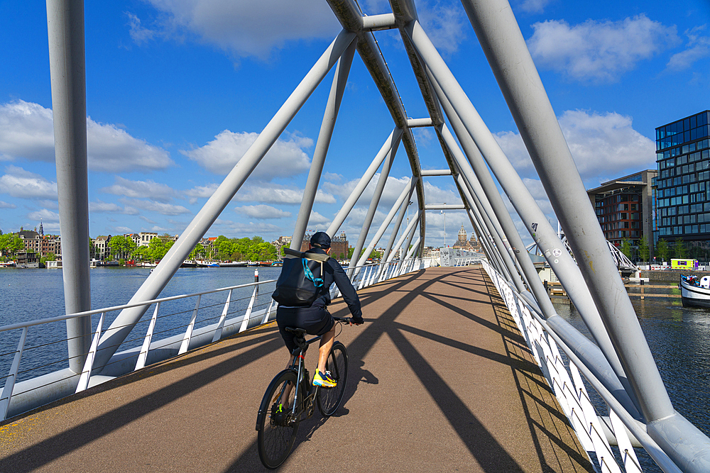 Man on bicycle riding on Mr. J.J. van der Veldebrug bridge, Amsterdam, The Netherlands