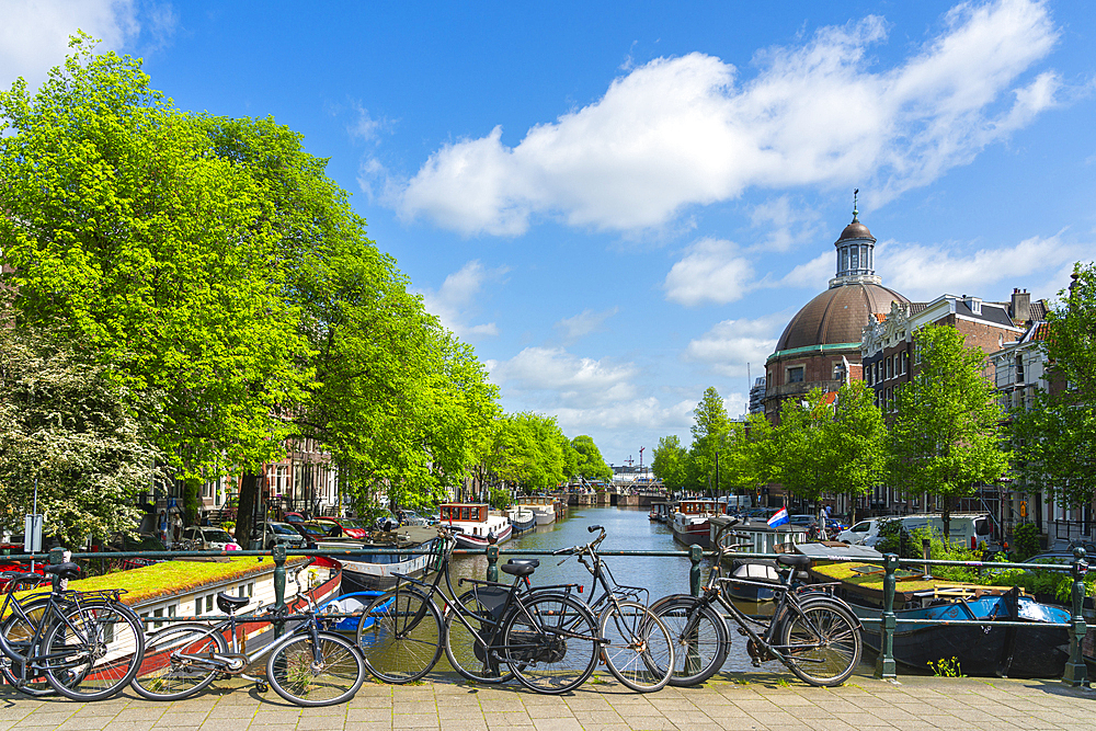 Bikes on Corsgenbrug bridge over Singel canal and Renaissance dome of Koepelkerk Church in the background, Amsterdam, The Netherlands, Europe