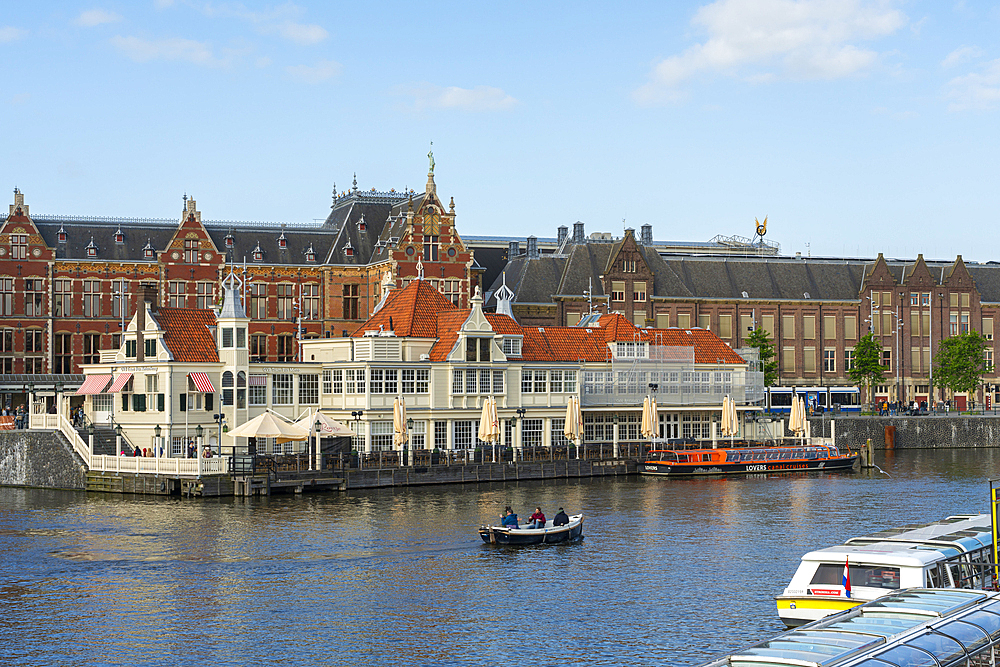 Boat on canal in front of Amsterdam Central Train Station, Amsterdam, The Netherlands, Europe