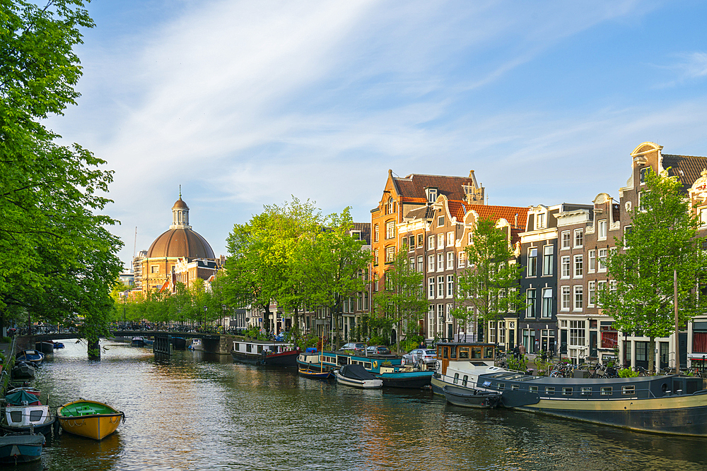 Houses by Singel canal and Renaissance dome of Koepelkerk Church in the background at sunset, Amsterdam, The Netherlands, Europe