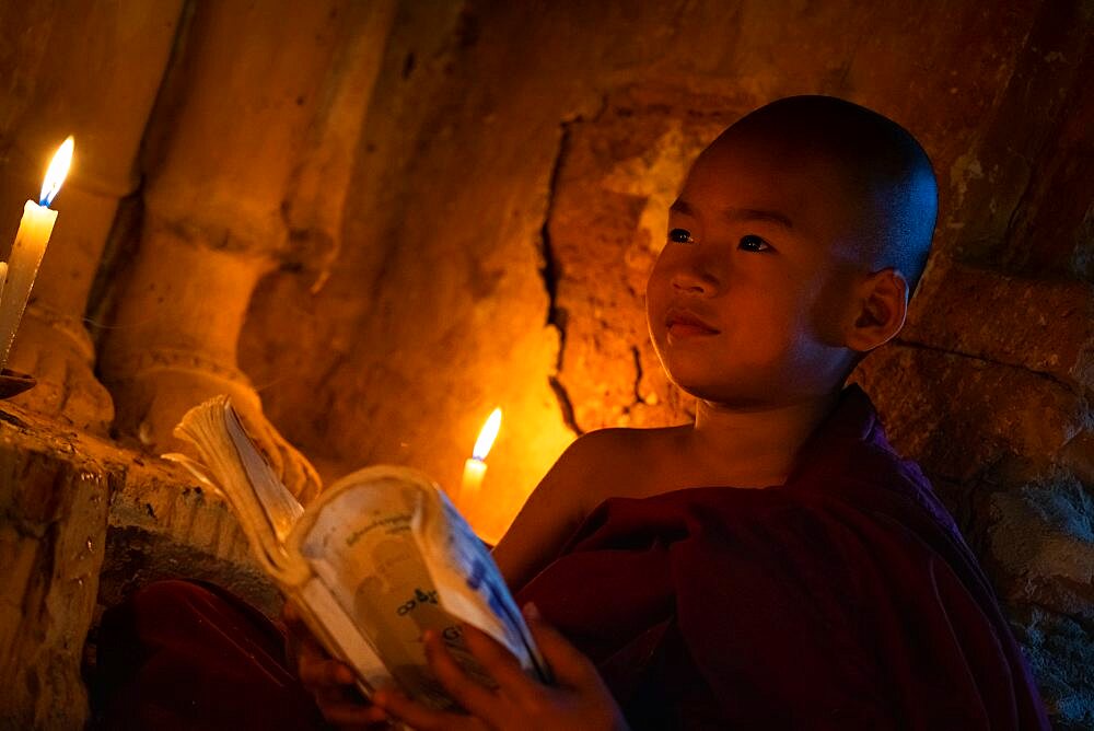 Young monk holding book inside temple, Bagan, Myanmar