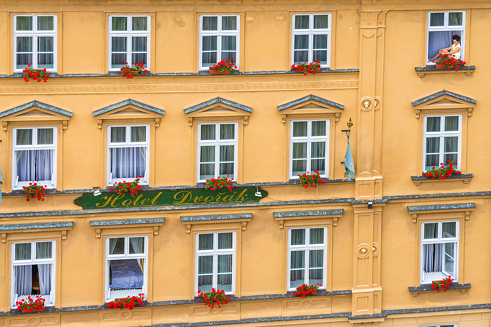 Woman sitting in window of house in historical center of Cesky Krumlov, UNESCO World Heritage Site, Cesky Krumlov, South Bohemian Region, Czech Republic (Czechia), Europe