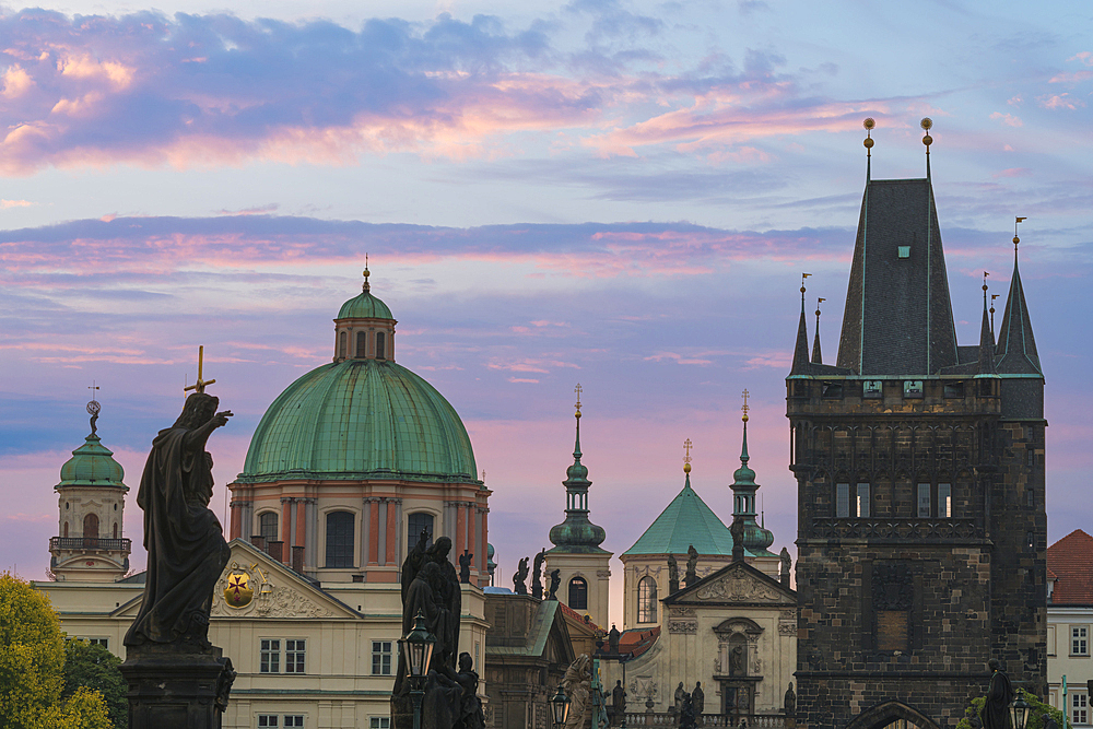 Details of statues and spires at Charles Bridge at sunrise, featuring dome of Church of Saint Francis of Assisi and Old Town Bridge Tower, UNESCO World Heritage Site Prague, Bohemia, Czech Republic (Czechia), Europe