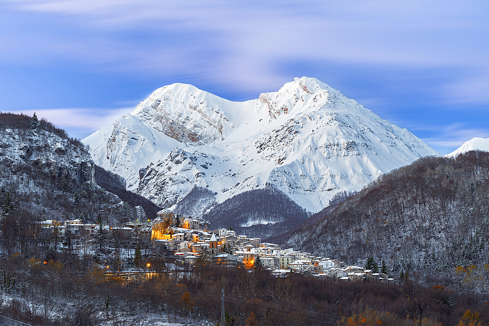 The small illuminated village of Pietracamela covered with snow and surrounded by Intermesoli snowy peak at dusk, Gran Sasso and Monti della Laga National Park, Apennines, Teramo district, Abruzzo region, Italy, Europe