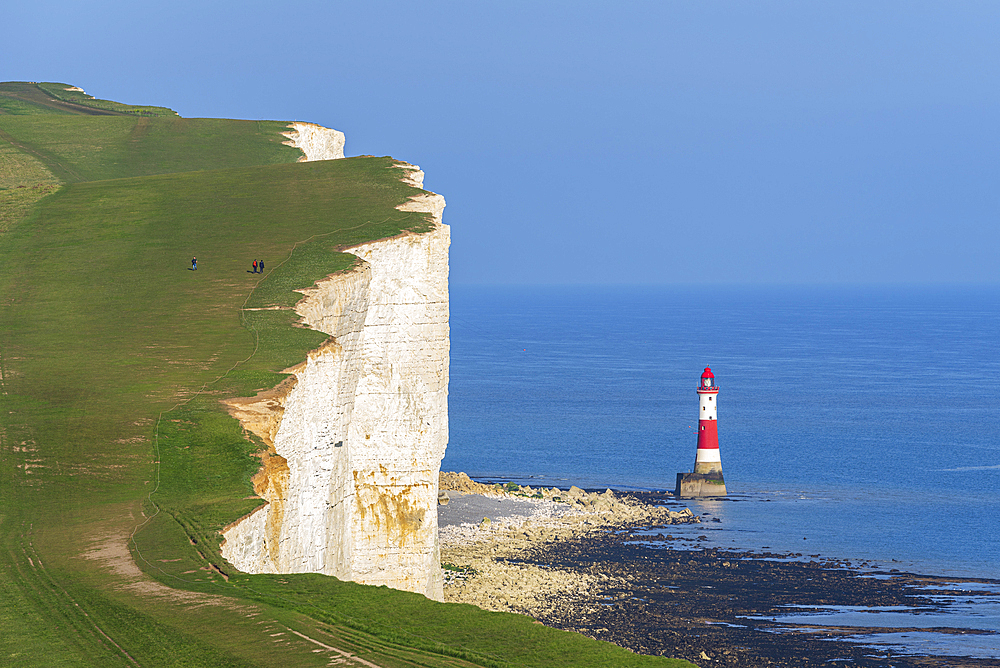 View of the coast of the Seven Sisters white chalk cliffs with the Beachy Head lighthouse in the background, South Downs National Park, East Sussex, England, United Kingdom, Europe