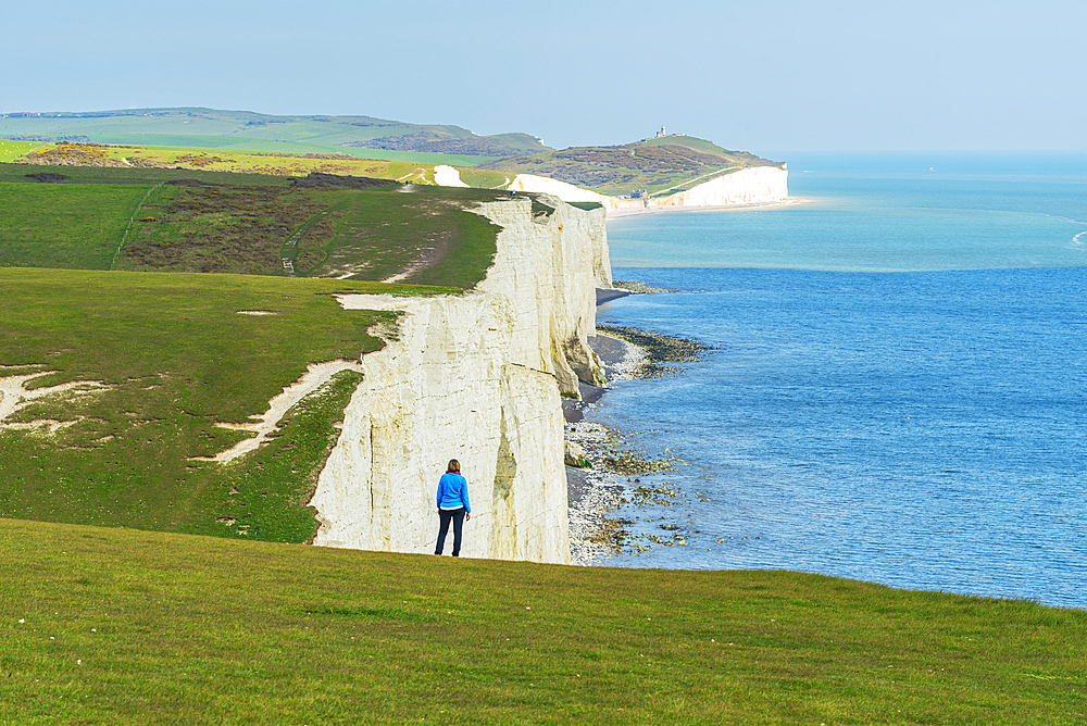 Rear view of woman admiring the view of the coast along the Seven Sisters chalk cliffs, South Downs National Park, East Sussex, England, United Kingdom, Europe