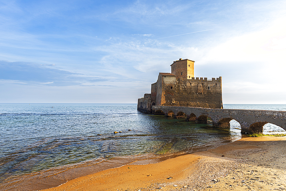 Torre Astura castle rising above the water of the Tyrrhenian Sea seen from the golden beach at sunset, Rome province, Latium (Lazio), Italy, Europe