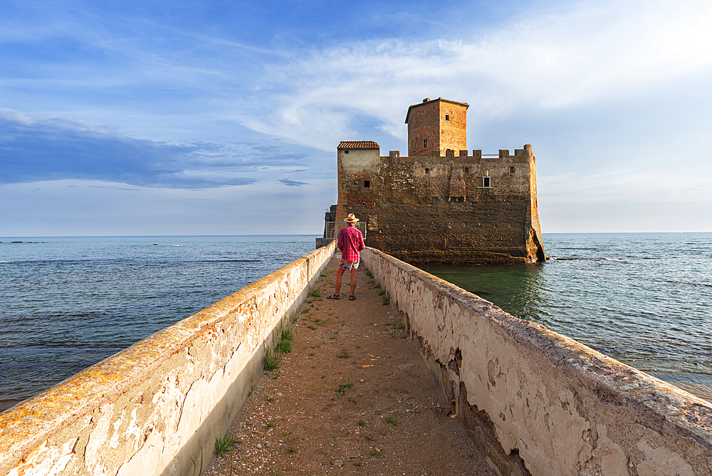 Tourist standing on top of the boardwalk admiring Torre Astura Castle, Nettuno municipality, province of Rome, Tyrrhenian sea, Latium (Lazio), Italy, Europe