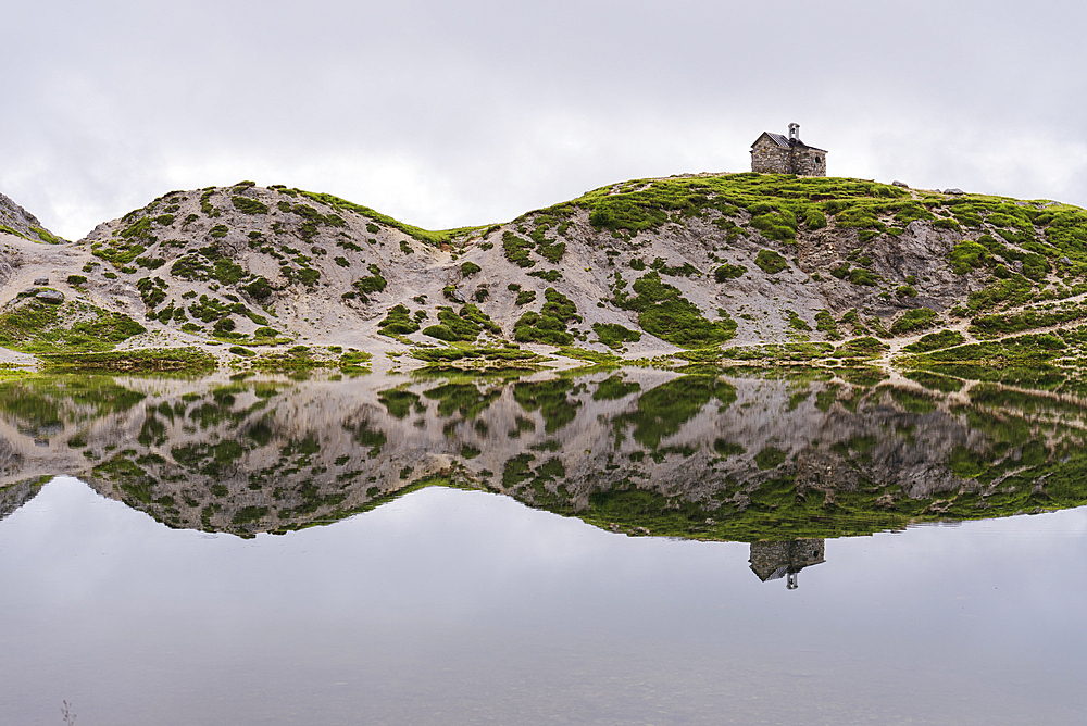 The small church and the reflection of the alpine landscape in the calm water, Olbe lakes, Sappada, Carniche Alps, Udine province, Friuli-Venezia Giulia, Italy, Europe