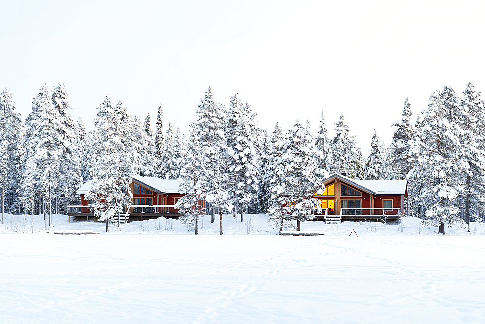 Winter view of a mountain lodge surrounded by frozen forest covered with snow in Swedish Lapland, Sweden, Scandinavia, Europe