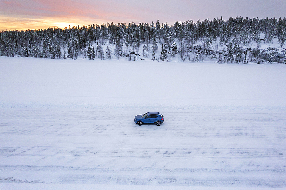 Drone shot of a blue SUV car standing in the middle of an empty frozen lake in the winter scenery of the Arctic Circle, Jokkmokk, Norrbotten, Swedish Lapland, Sweden, Scandinavia, Europe