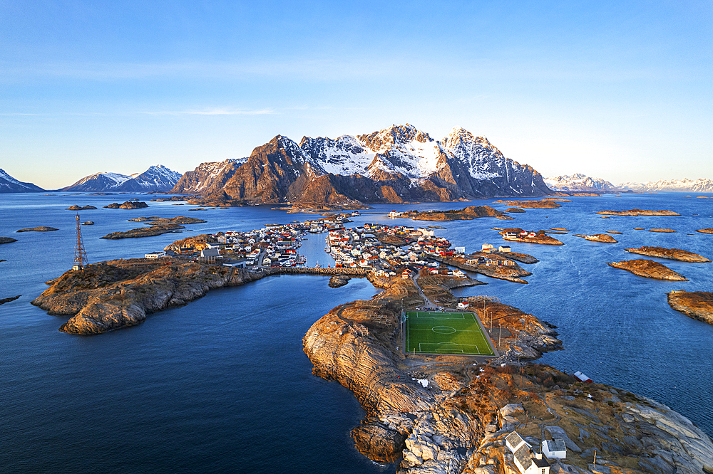 Sunset over the small village of Henningsvaer surrounded by snowy massif with the famous soccer field in the foreground, Henningsvaer, Vagan municipality, Nordland, Lofoten Islands, Norway, Scandinavia, Europe