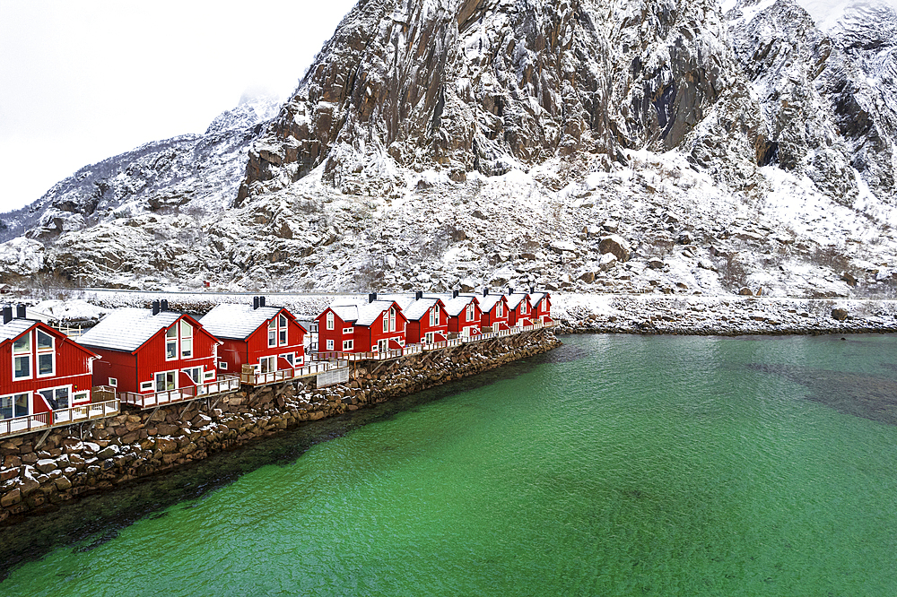 Typical wooden rorbu in winter scenery by the emerald water of the fjord, Svolvaer, Lofoten Islands, Norway, Scandinavia, Europe