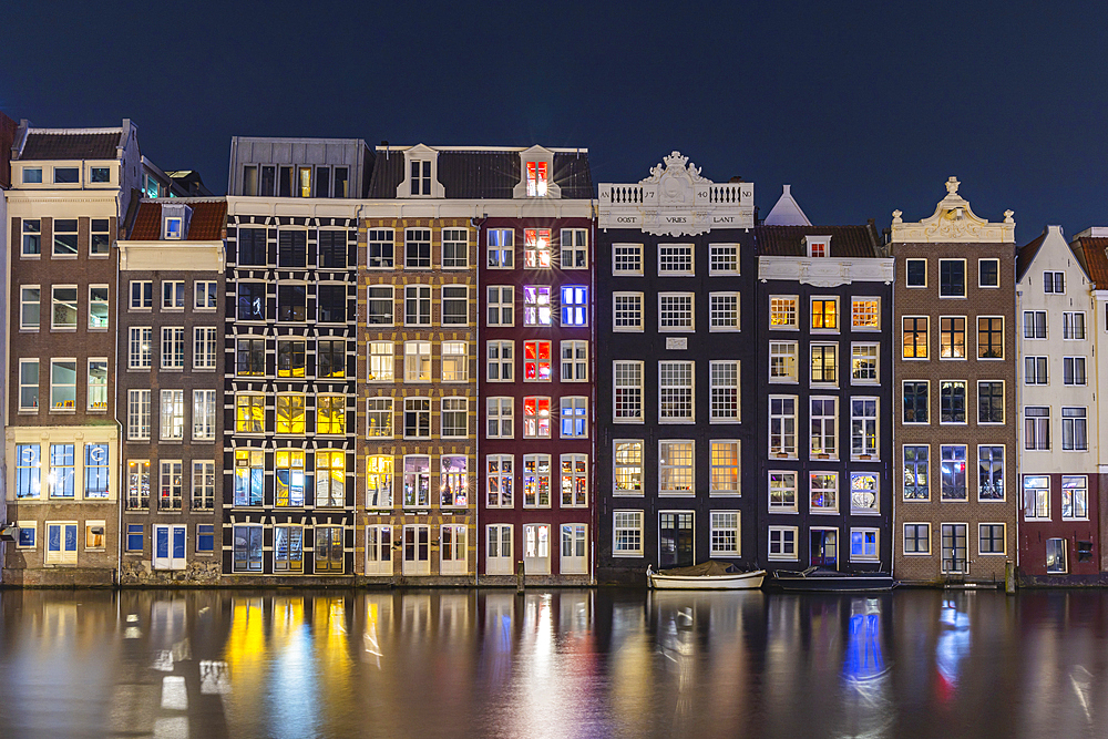 Europe, Netherlands, North Holland, Amsterdam. Lights at night in traditional row houses on a canal in Amsterdam.