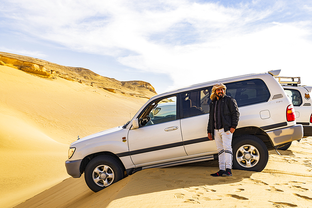 Wadi al Hitan, Faiyum, Egypt. SUVs on the edge of a dune at Wadi el-Hitan paleontological site.