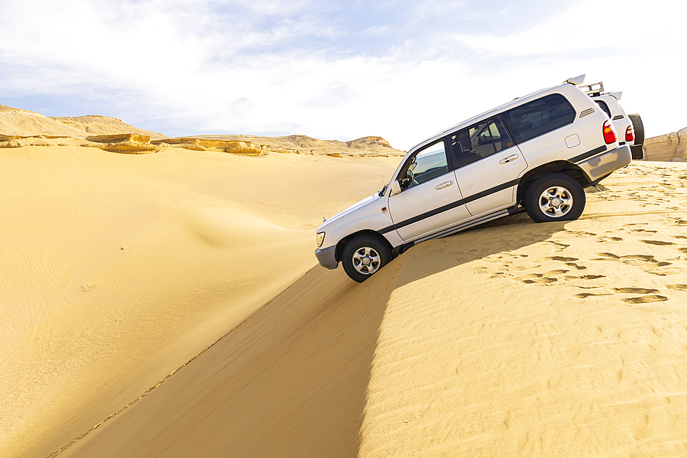 Wadi al Hitan, Faiyum, Egypt. February 20, 2022. SUVs on the edge of a dune at Wadi el-Hitan paleontological site.