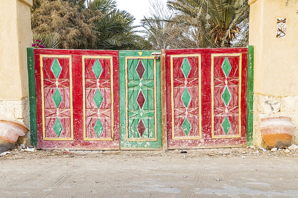 Faiyum, Egypt. Red and green painted wooden gate in a wall in the village of Faiyum.