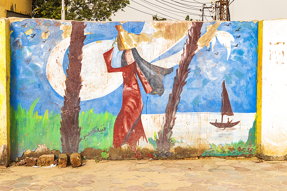 Faiyum, Egypt. February 19, 2022. Mural of a woman carrying water on a wall in Faiyum.