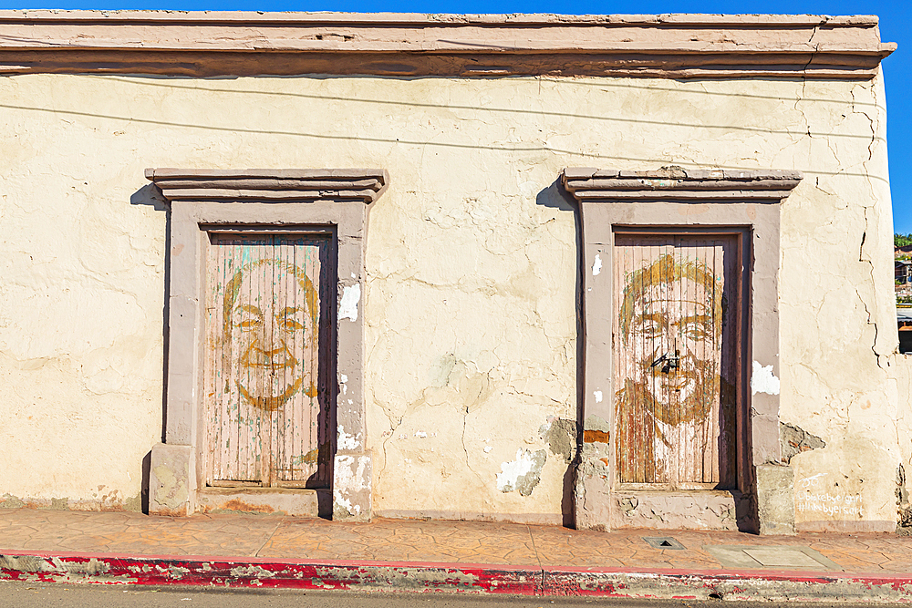 Mulege, Baja California Sur, Mexico. November 14, 2021. Murals of large faces on the doors of an old bulding.