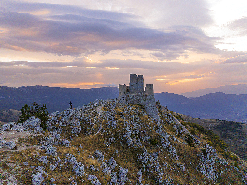 A person admires the Rocca Calascio castle during an autumn sunrise, National Park of Gran Sasso and Monti of Laga, Abruzzo, Italy, Europe