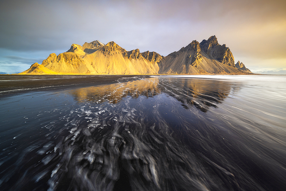 Reflection of Vestrahorn mountain over black sand at sunrise in spring, Stokksnes peninsula, Hofn, Austurland, Iceland, Polar Regions