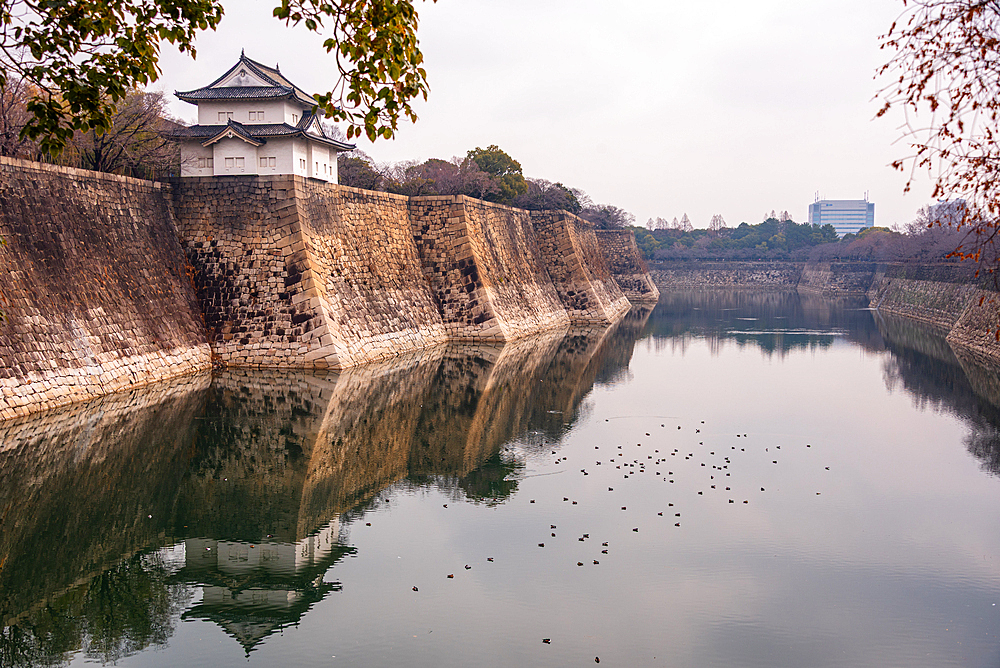 Osaka Castle in Japan. Overlooking the stone moat and reflecting water at Rokuban-yagura Turret on the outer walls.Framed by late autumanl foliage