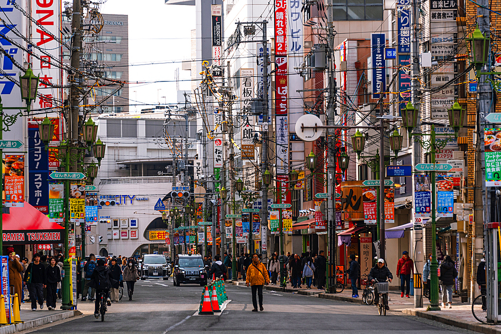 A busy street full of neon lights and advertisement signs filled with colorful signs, power lines, pedestrians, and vibrant city life in Osaka, Kansai, Japan. Nipponbashi Denden Town