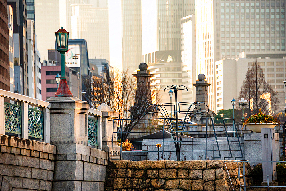 Close up of a traditional stone bridge with modern facades of skyscrapers in the background Nakanoshima in Osaka, Japan. A green Island park in the center of Osaka.