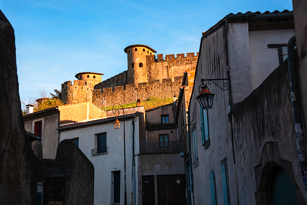 Old town in Rue Trivalle looking along the street with the castle in the background. Evening atmosphere in Carcassonne, Languedoc-Roussillon, France