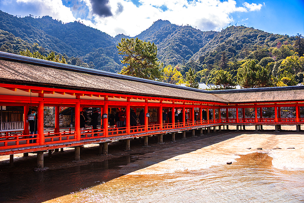Covered Wooden Corridor of Itsukushima Shrine Framed by Lush Mountains on Miyajima Island, Japan