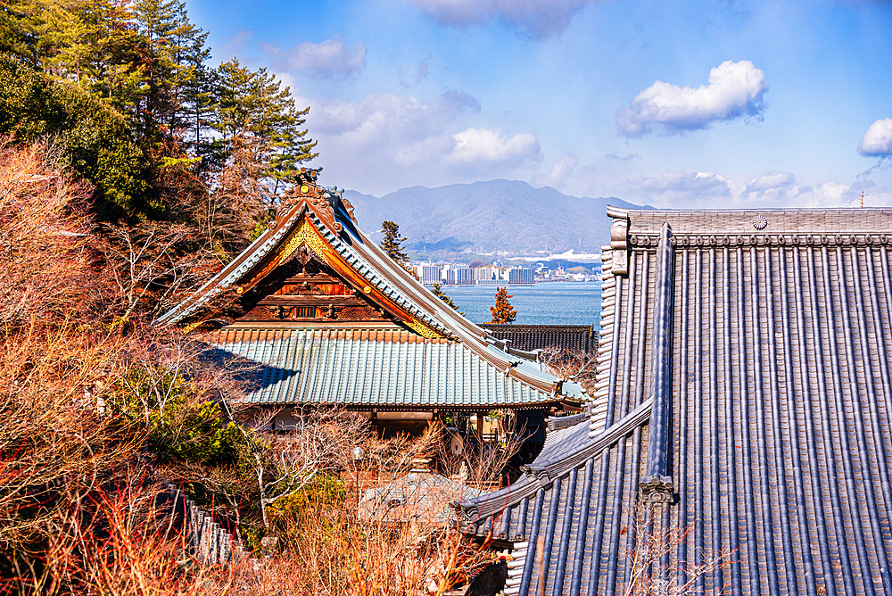 Traditional Rooftops of Daishoin Temple Framed by Trees with View of Seto Inland Sea on Miyajima Island, Japan