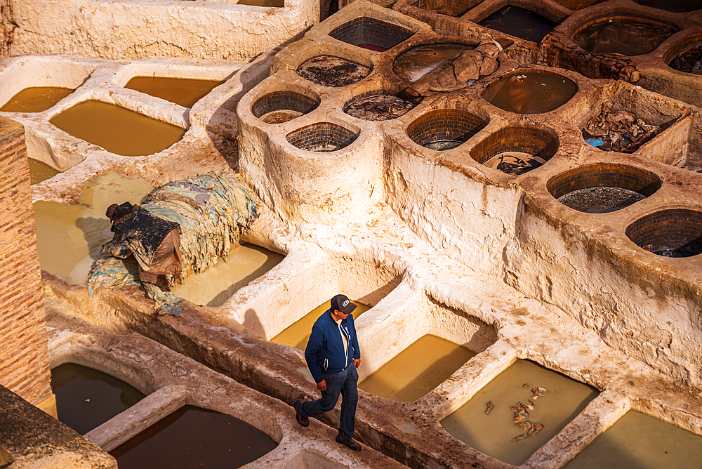Man Walking Along Edge of Dye Pits at Chouara Tannery with Whitewashed Walls in Fes, Morocco