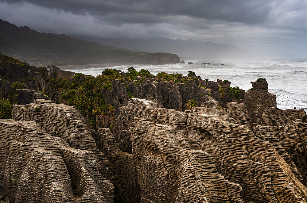 Layered Limestone Columns of Pancake Rocks With Misty Coastline in the Background, Paparoa National Park, New Zealand
