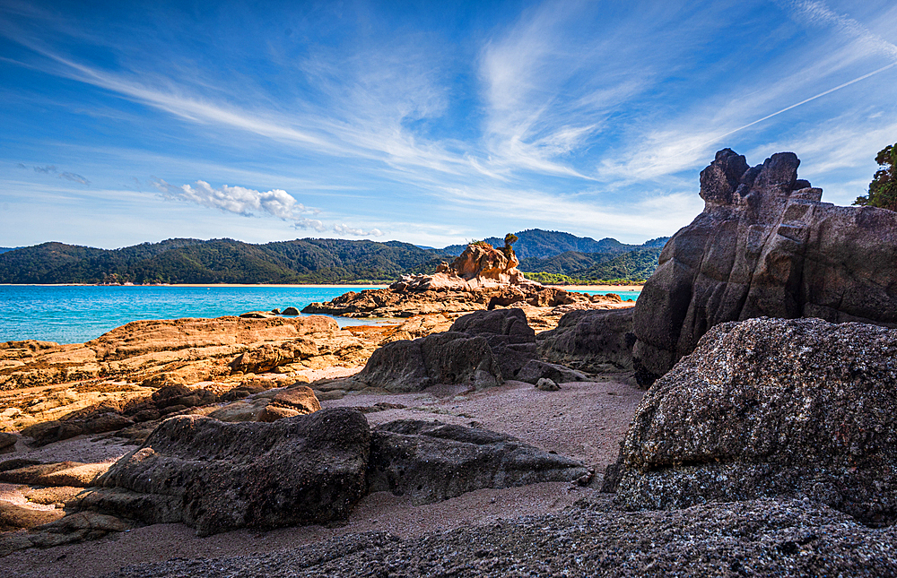 Golden Light Over Sculpted Coastal Rocks and Clear Blue Sea at Abel Tasman National Park, New Zealand