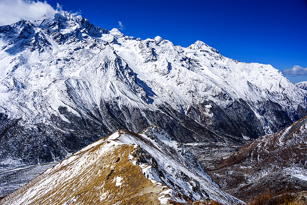 Aerial view of ridgeline leading toward rugged snow-covered mountains above Langtang Valley near Kyanjin Gompa, Nepal. Summit of Lower Kyanjn Ri