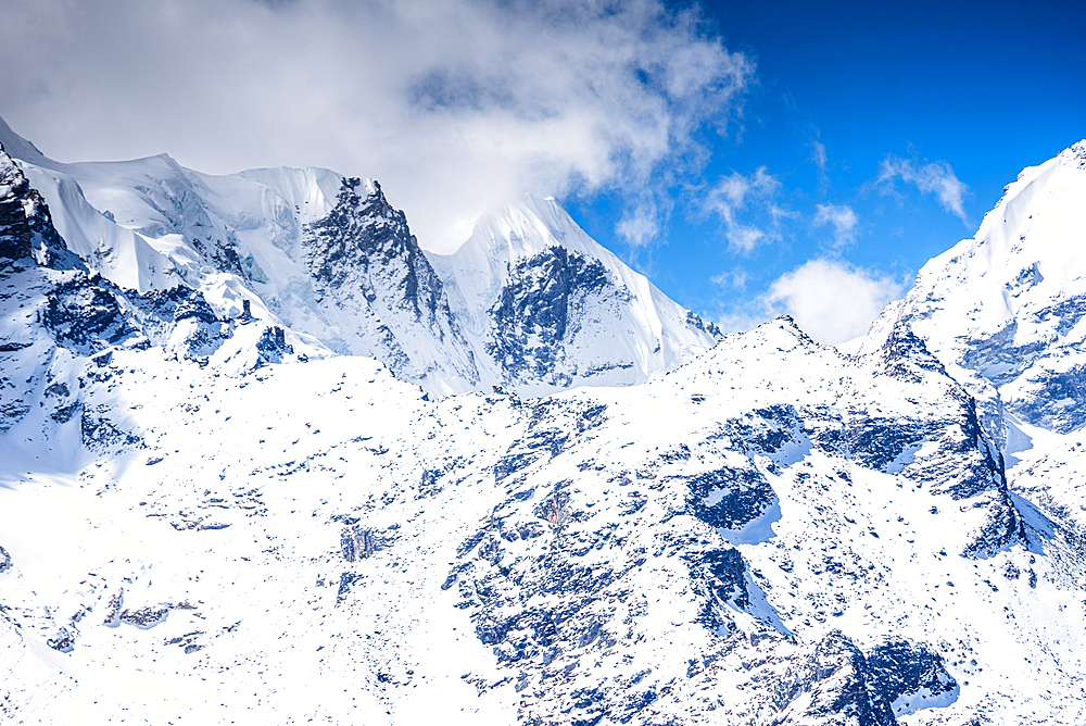 Glaciated Slopes and Jagged Himalayan Summits Viewed from the Kyanjin Ri Summit under a Bright Blue Sky with Scattered Clouds