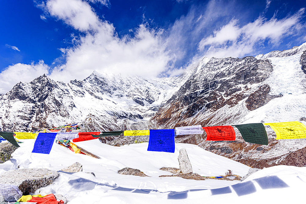 Colorful Tibetan Prayer Flags Fluttering on the Snowy Summit of Kyanjin Ri with Langtang Lirung Towering in the Background on a Clear Winter Day