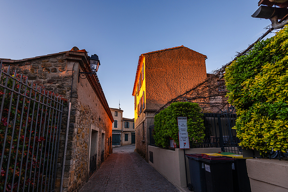 Early evening light along a narrow lane between stone houses in La Bastide Saint-Louis, Carcassonne