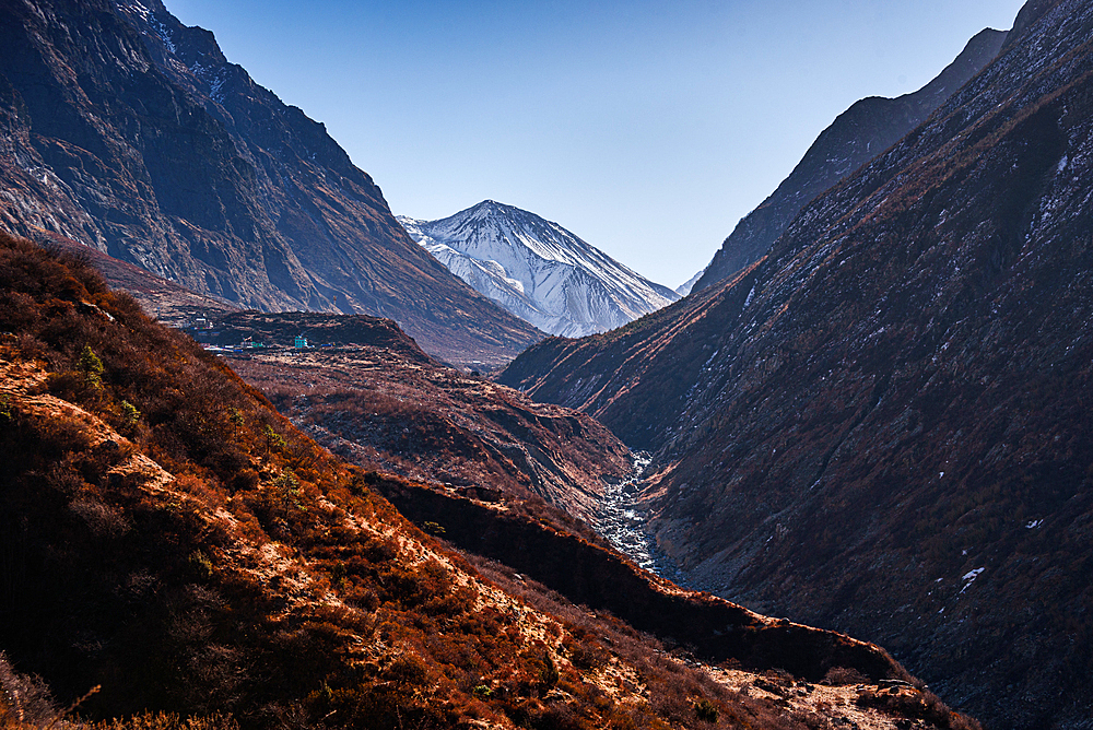 Panoramic trail view toward snow-covered Tserko Ri peak with steep ridges and valley terrain in Langtang Valley, Nepal