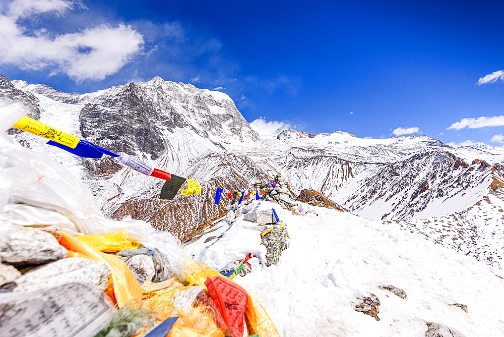 Colorful prayer flags draped along the snow-covered summit of Kyanjin Ri with Langtang lirung slopes in the background, Langtang Valley