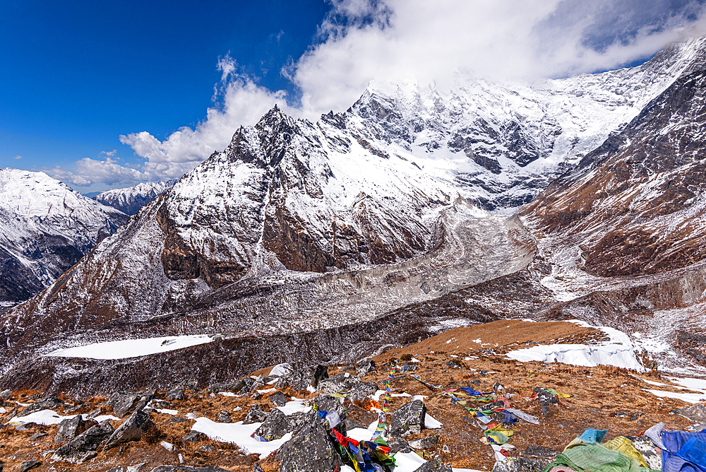 Dramatic view of Langtang Lirung glacier beneath towering Himalayan peaks and prayer flags from Kyanjin Ri, Langtang Valley