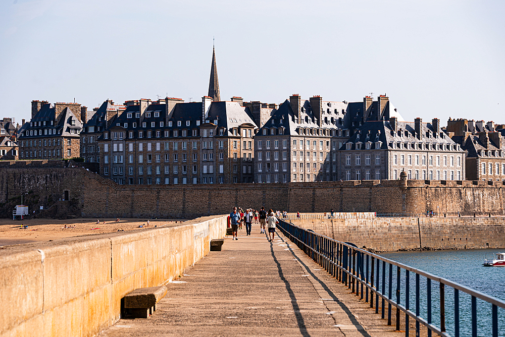 Panoramic view of Saint-Malo’s historic walled city and seafront ramparts, Brittany, France, with waves against the stone walls