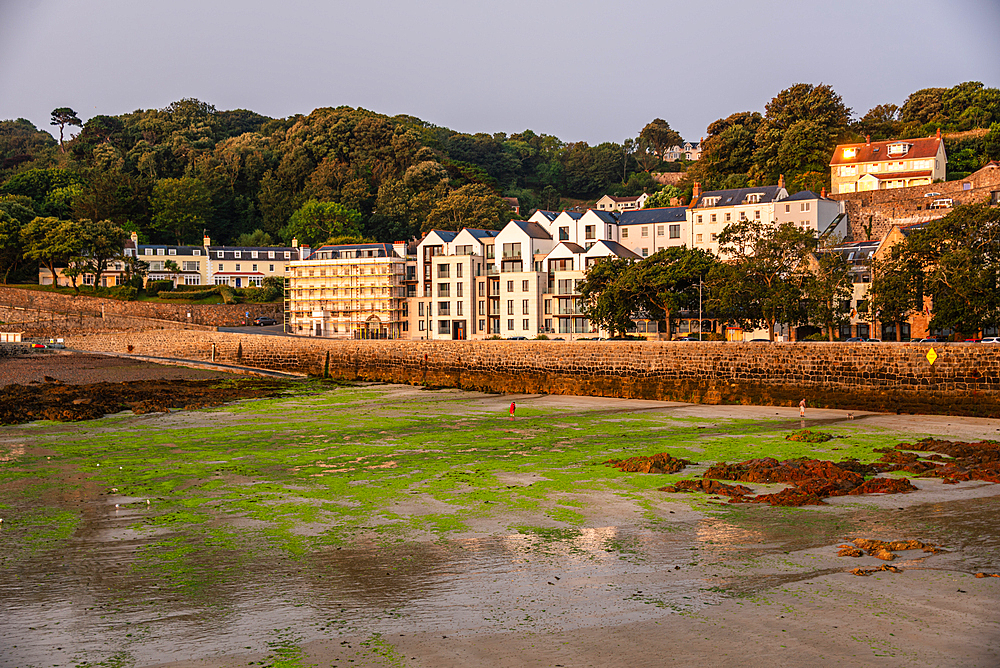 Scenic St Peter Port Guernsey harbourfront with hillside houses tidal flats and tranquil maritime character at sunset on the Channel Islands