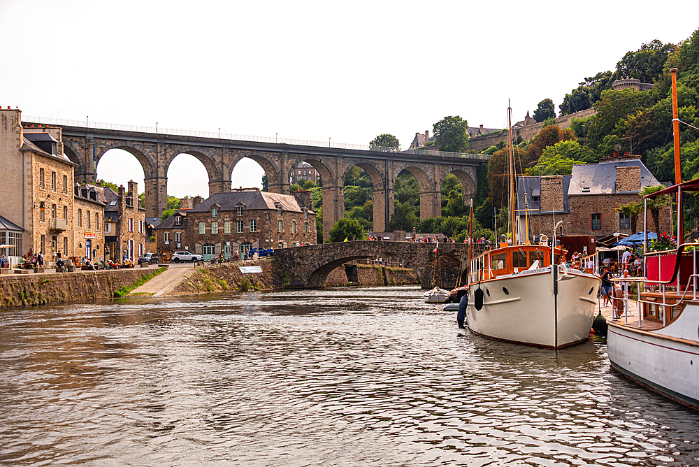 River Rance with boats sailing under Dinan viaduct and old stone bridge Brittany France
