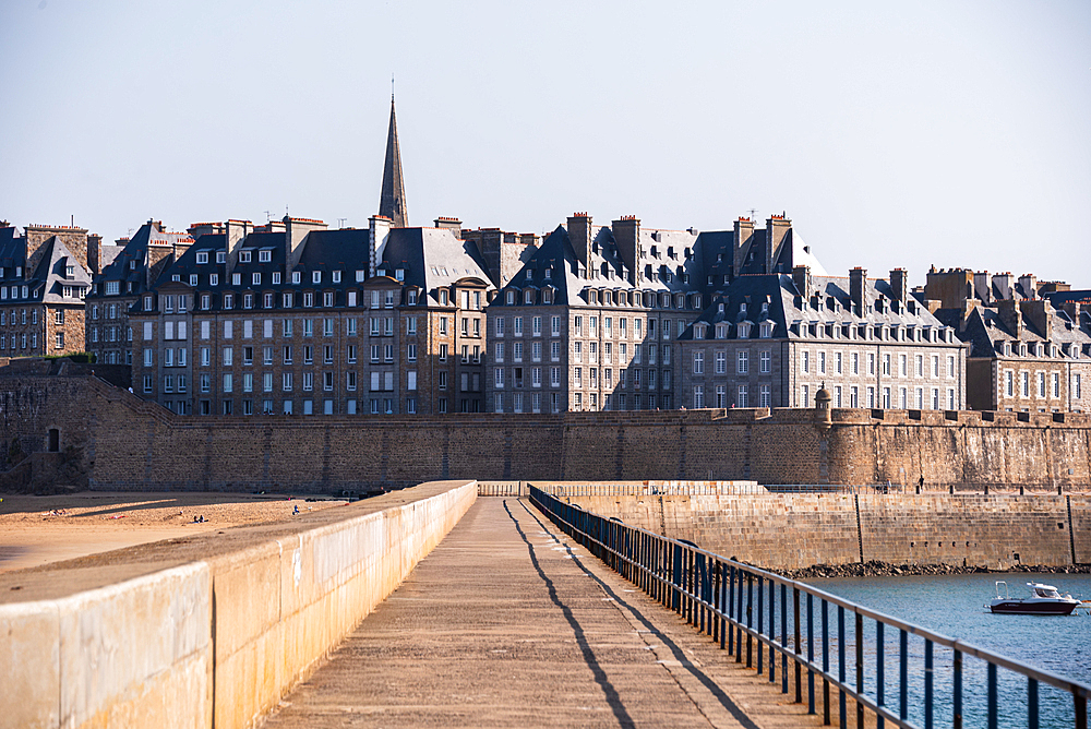 Historic fortified walls and spire of Saint-Malo seen from stone pier Brittany France