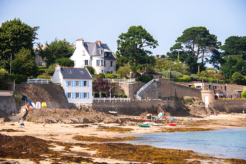 View of elegant seaside villas and traditional Breton houses facing the coastline in Rothéneuf near Saint-Malo. The rocky beach and tidal waters highlight Brittany’s distinctive landscape