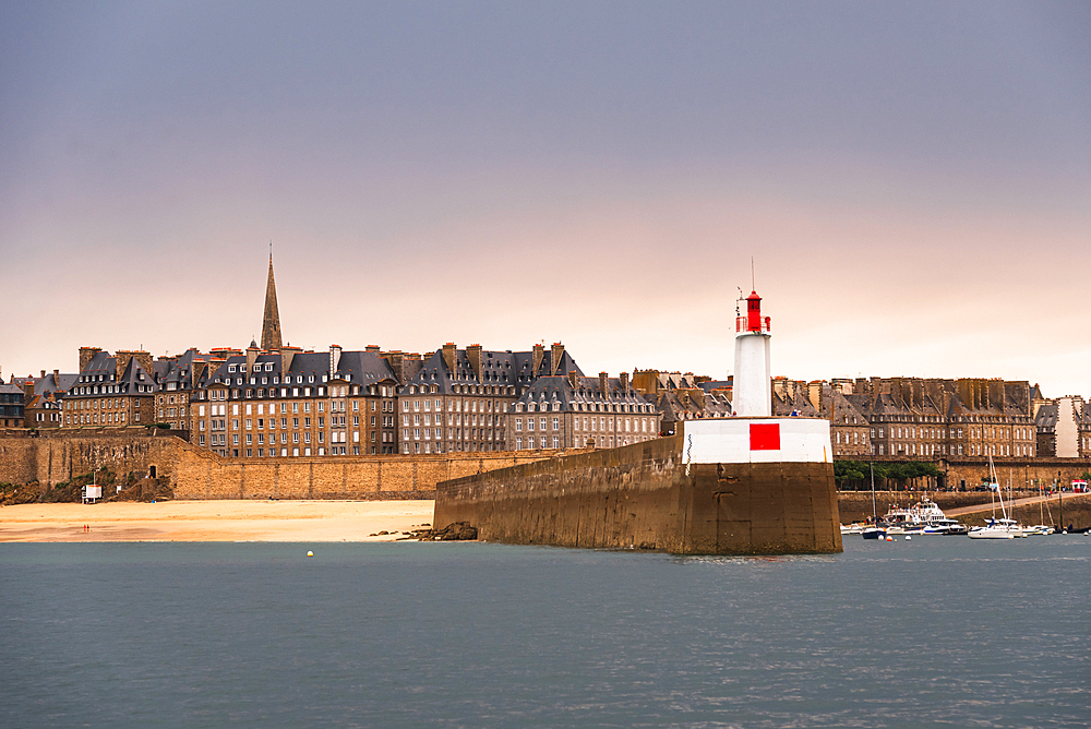 Lighthouse and stone jetty at the entrance of Saint Malo harbor with view of fortified old town Brittany France