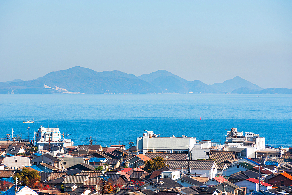 Coastal city roof tops, a calm blue sea and islands on the horizon, Tomonoura, Honshu, Japan, Asia